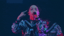 a woman singing into a microphone while wearing a shirt that says ' i love you ' on it