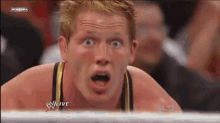 a wrestler is making a surprised face during a wrestling match .