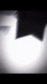 a shadow of a person 's face is cast on a white surface