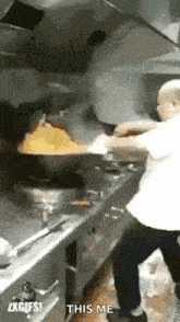 a man is cooking food in a wok in a kitchen while a fire is coming out of it .