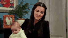a woman is holding a baby in front of a picture of a baby