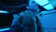 a woman in a fur coat is standing in a dark room