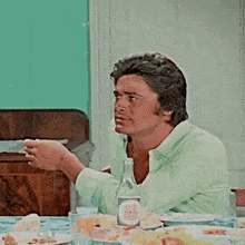 a man sits at a table with plates of food and a bottle with a label that says yum ram