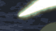 a white light beam is coming out of the sky in a dark cloudy sky .