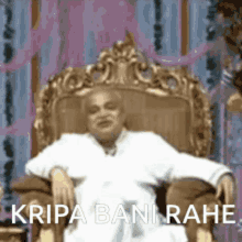 a man is sitting in a chair with his arms outstretched and the words kripa bani rahe written on the bottom .