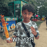 a boy holding a skewer of food with the words what written on the bottom