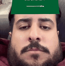 a man with a beard and mustache is wearing a green flag over his head .