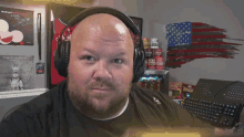 a bald man with a beard wearing headphones looks at the camera