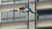 a person in a blue skirt is flying through the air in front of a building