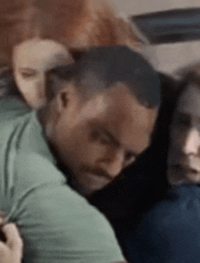 a man in a green shirt is hugging another man in a blue shirt .