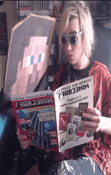a man wearing sunglasses is reading a magazine that says minecraft