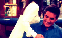 a man in a blue shirt is smiling while a woman in a white shirt holds his arm