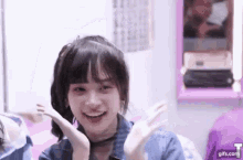 a young girl is smiling and waving her hands in front of a mirror in a bedroom .