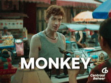 a man in a tank top is talking to a woman in front of a sign that says monkey on it