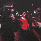 a group of people standing in front of a car at night .