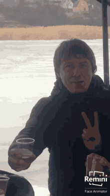 a man is giving a peace sign while holding two cups of liquid