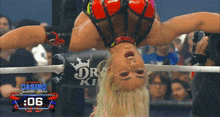 a female wrestler is doing a handstand in a ring with the number : 06 on the bottom