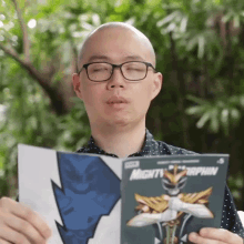 a bald man wearing glasses is reading a mighty morphin comic