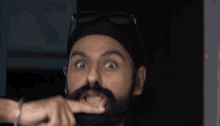 a man with a beard wearing sunglasses and a turban is making a funny face