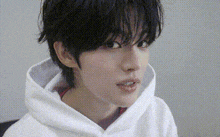 a close up of a person wearing a white hoodie and looking at the camera .