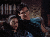 a man and a woman are laying on a couch and the man has glasses on
