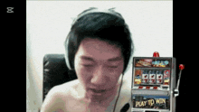 a man wearing headphones next to a play to win slot machine
