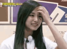 a woman with long hair is scratching her forehead .