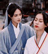 two women are standing next to each other and one of them is wearing a blue robe .
