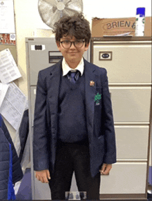 a boy in a school uniform is standing in front of a filing cabinet that says brien on it