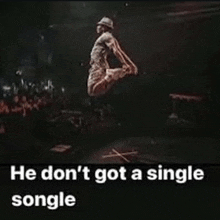 a man in a hat is jumping in the air on a stage in front of a crowd ..