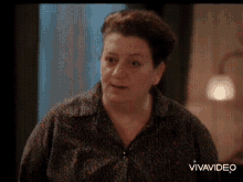 a woman in a polka dot shirt is talking to someone in a video .