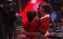 a man in a red shirt that says ' war ' on the back is hugging another man