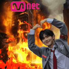 a man making a heart shape with his hands in front of a mnet sign