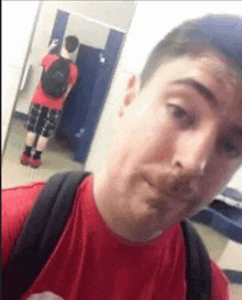 a man is taking a selfie in a bathroom with a backpack .
