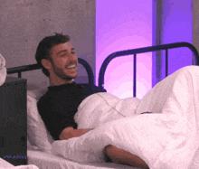 a man laying on a bed with a purple light behind him and the name smhashley on the bottom right