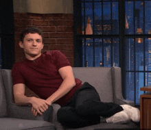 a man in a maroon shirt sits on a couch