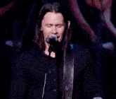 a man singing into a microphone while playing a guitar