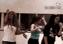 three women are dancing in front of a screen that says 0 : 09 : 49