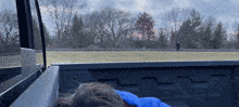 a person is sleeping in the back of a truck with a blue blanket