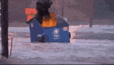 a blue dumpster with a fire coming out of the top