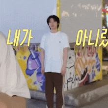a man in a white shirt stands in front of a wall with yellow letters that say lh7