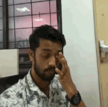 a man with a beard is rubbing his eyes and wearing a watch