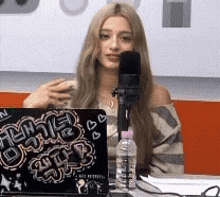 a woman is sitting in front of a microphone in front of a laptop that says ' 2ntv ' on it