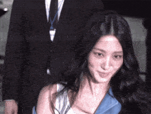 a woman with long black hair is smiling in front of a man in a suit and tie