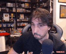 a man sitting in front of a microphone with the words think jules on the bottom right