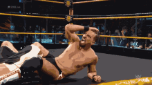 a shirtless wrestler is laying on the ground in a wrestling ring with the hashtag # 205live