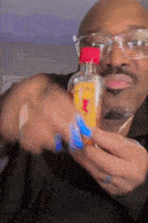 a man wearing glasses is holding a small bottle with a yellow label that says ' honey ' on it