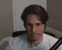 a man in a white shirt is sitting in a chair with a microphone in front of him .