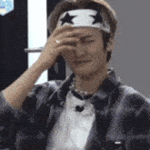 a man wearing a headband with stars on it is covering his eyes