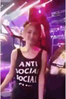 a woman is wearing a black tank top that says anti social social .